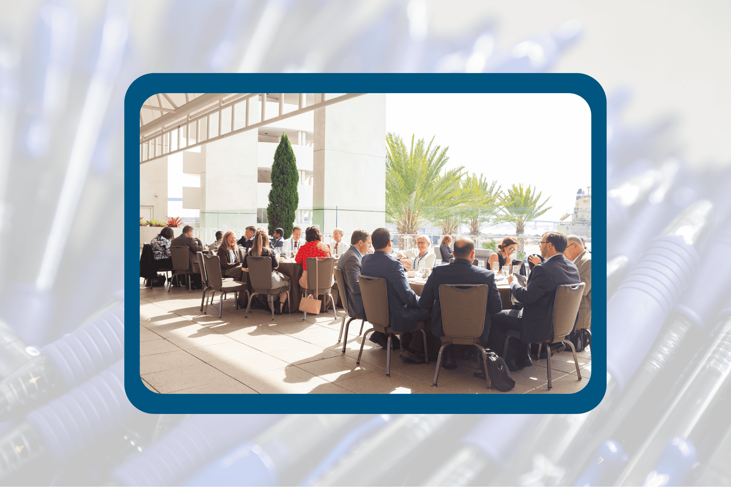 Attendees talking at tables during a meal with palm trees in the background