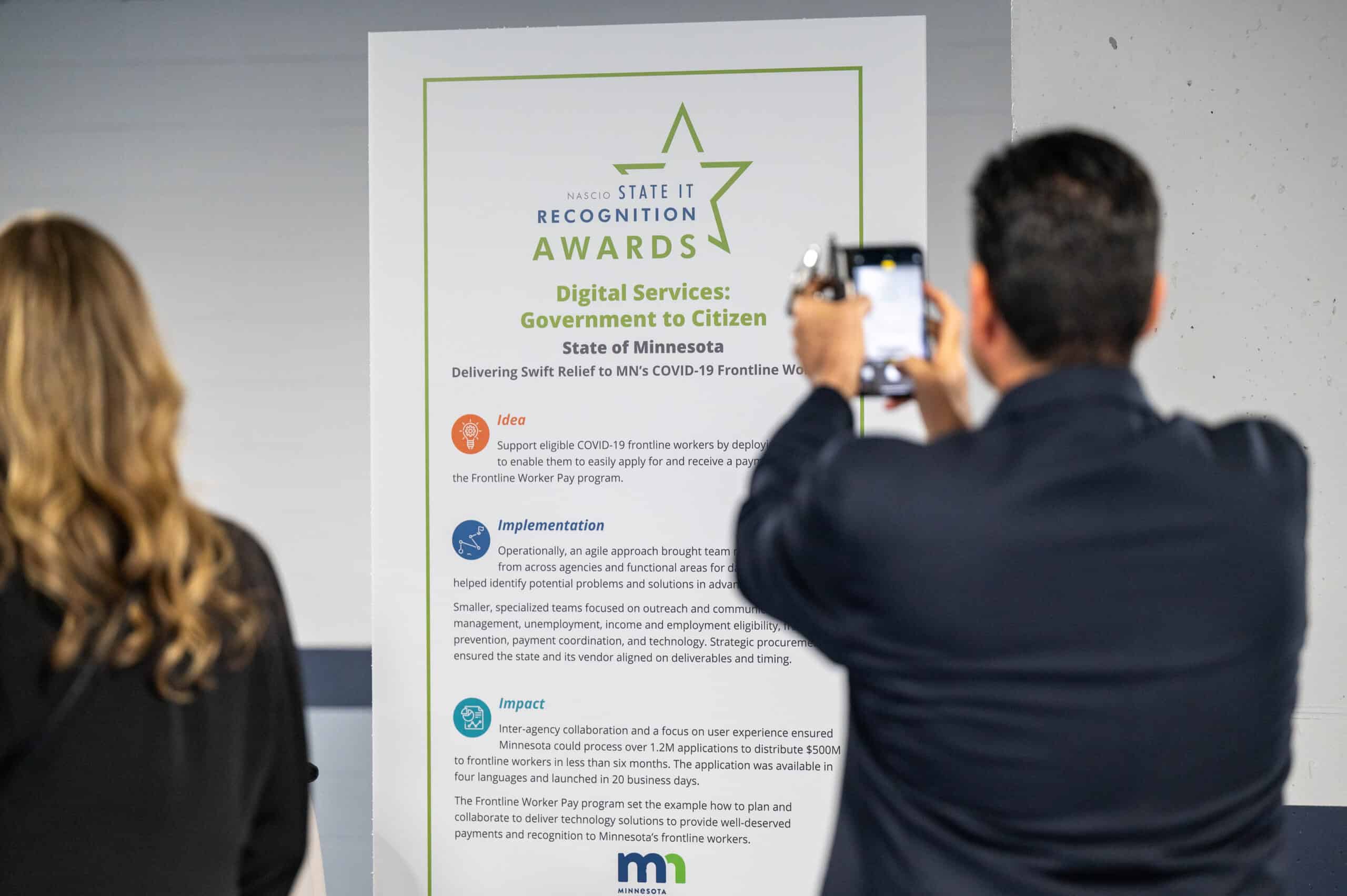 Attendee photographing Award recipients signage